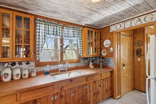 kitchen featuring wood ceiling, butcher block counters, freestanding refrigerator, and a sink