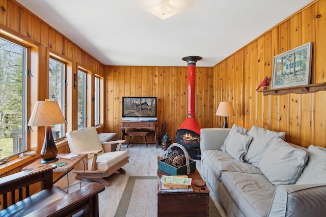 living area featuring wood finished floors, wood walls, and a wood stove