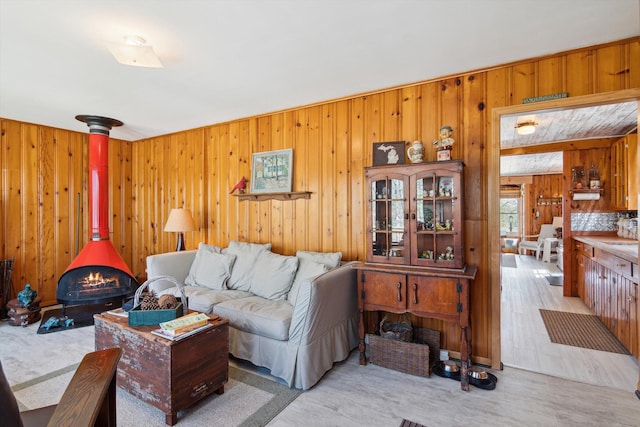 living room with wood finished floors, a wood stove, and wood walls