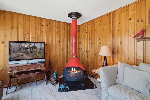 living area with a wood stove, wood finished floors, and wooden walls