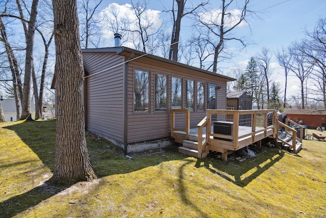 rear view of property with a storage unit, a lawn, an outbuilding, and a deck