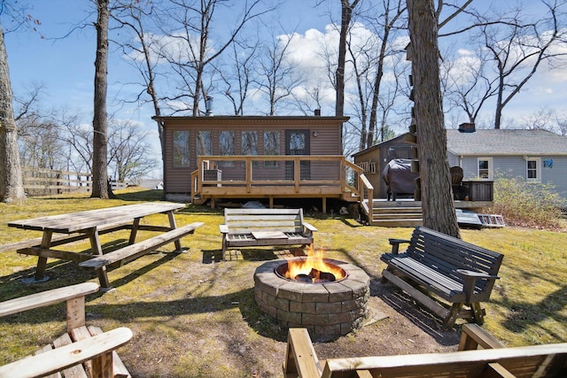 rear view of property with a wooden deck and an outdoor fire pit