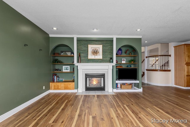 7174 Loma Linda Dr, Rockford, MI 49341 - unfurnished living room featuring a fireplace with flush hearth, baseboards, wood finished floors, stairs, and a textured ceiling