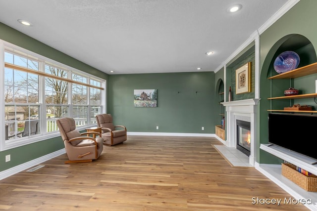 7174 Loma Linda Dr, Rockford, MI 49341 - living area featuring a fireplace with flush hearth, baseboards, wood finished floors, crown molding, and recessed lighting