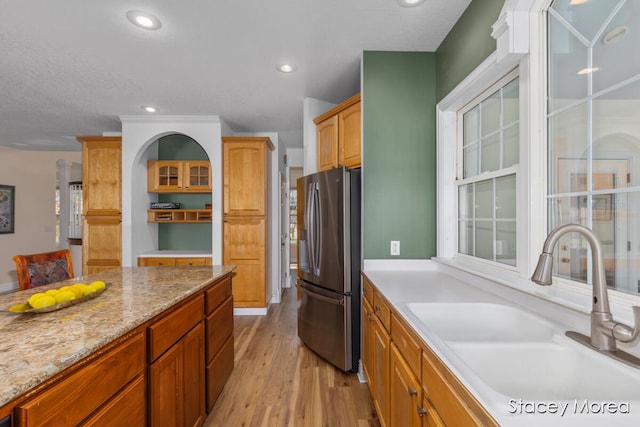 7174 Loma Linda Dr, Rockford, MI 49341 - kitchen with stainless steel fridge with ice dispenser, a sink, light wood-style floors, recessed lighting, and light stone countertops