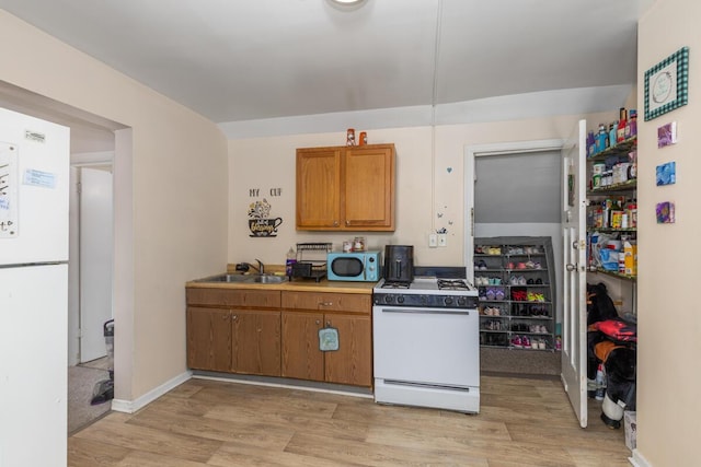 442 Emerald Ave NE, Grand Rapids, MI 49503 - kitchen with brown cabinetry, light wood-style flooring, white appliances, and a sink