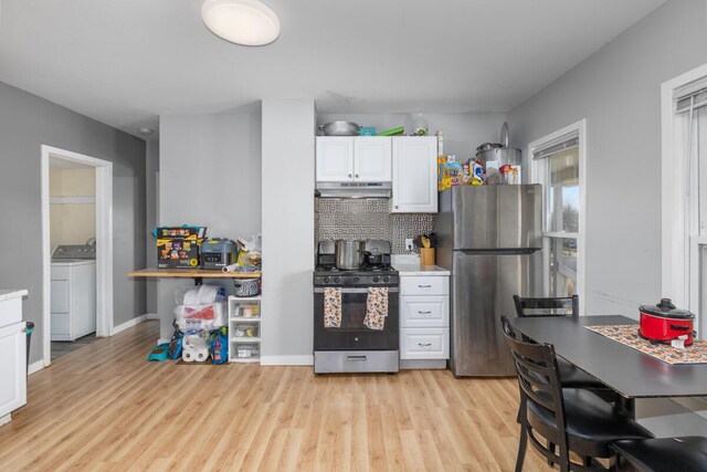 442 Emerald Ave NE, Grand Rapids, MI 49503 - kitchen with light wood-type flooring, washer / dryer, stainless steel appliances, white cabinetry, and under cabinet range hood