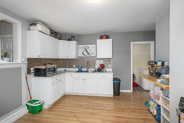 442 Emerald Ave NE, Grand Rapids, MI 49503 - kitchen featuring stainless steel microwave, tasteful backsplash, white cabinetry, and light wood-style flooring