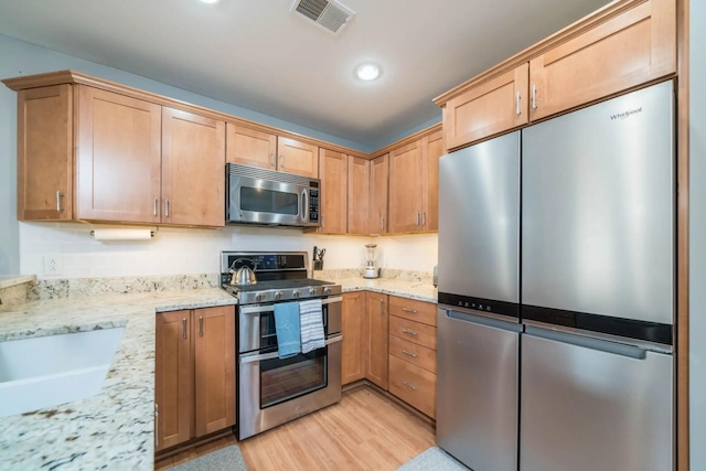 516 Williams St Unit 10, South Haven, MI 49090 - kitchen with light stone counters, visible vents, light wood finished floors, and stainless steel appliances