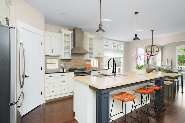 kitchen featuring a sink, dark wood-style flooring, wall chimney range hood, and stainless steel appliances