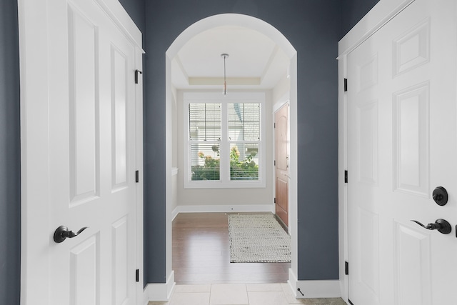 foyer featuring arched walkways, baseboards, and wood finished floors