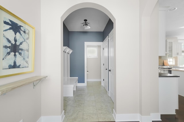 hall featuring arched walkways and baseboards