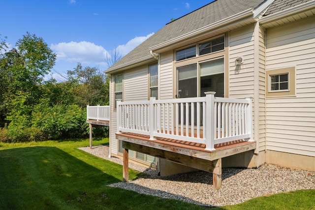 rear view of property with a lawn, a deck, and roof with shingles