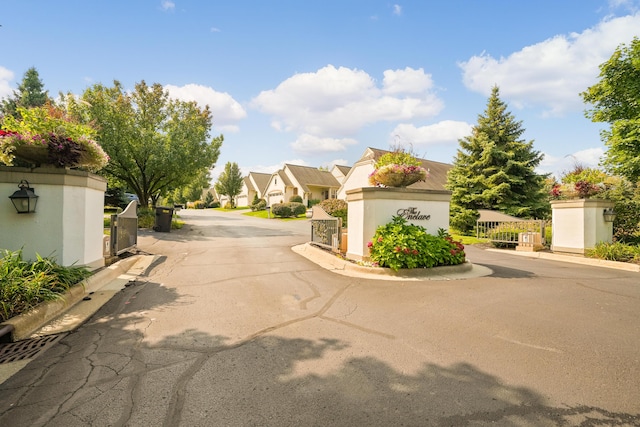 view of street with curbs, a gated entry, and a residential view