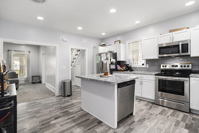 145 Kingsbury St, Athens, MI 49011 - kitchen featuring tasteful backsplash, light wood-style flooring, white cabinets, appliances with stainless steel finishes, and a kitchen island
