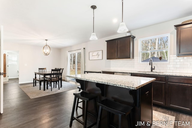 kitchen featuring dark brown cabinetry, decorative backsplash, a sink, and a wealth of natural light