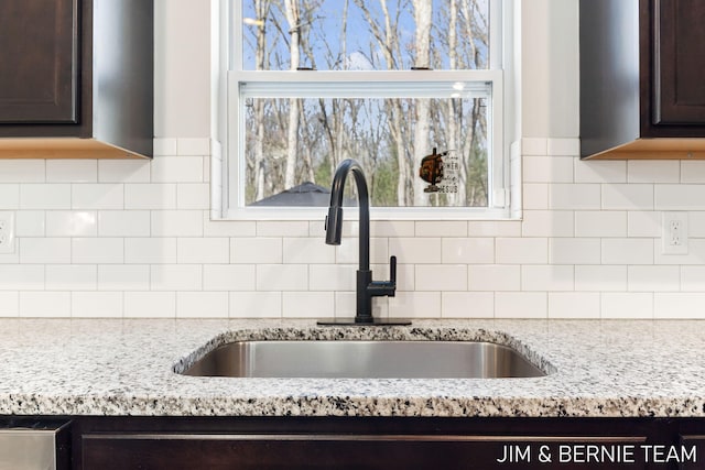 details with dark brown cabinetry, decorative backsplash, and a sink