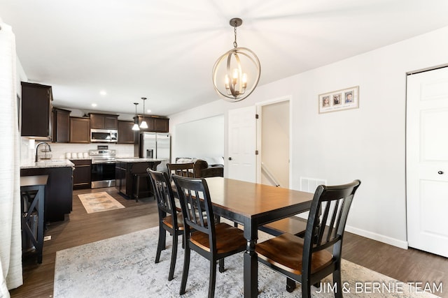 dining space with baseboards, dark wood-style flooring, a chandelier, and recessed lighting