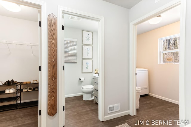 bathroom featuring wood finished floors, washer / dryer, baseboards, toilet, and visible vents