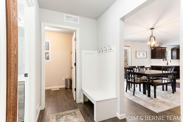 mudroom with a sink, a chandelier, baseboards, dark wood-style flooring, and visible vents