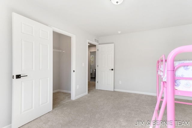 unfurnished bedroom featuring a spacious closet, a closet, carpet flooring, and baseboards