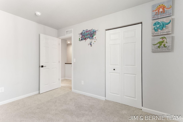 unfurnished bedroom featuring baseboards, carpet floors, visible vents, and a closet