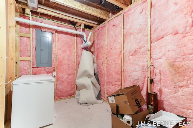 unfinished basement with electric panel, refrigerator, and visible vents