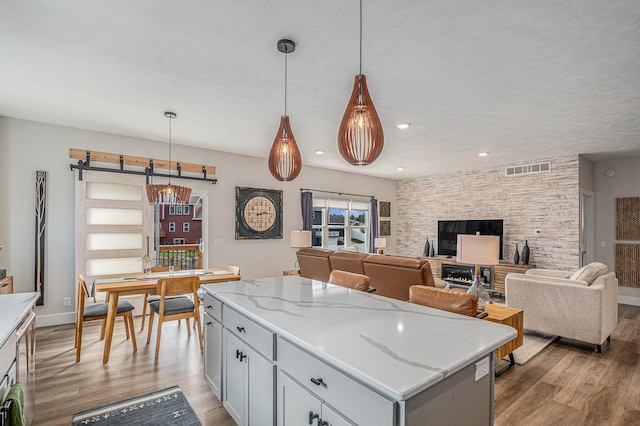 2537 Odawa Trl, Muskegon, MI 49444 - kitchen featuring visible vents, light wood-style floors, light stone countertops, a center island, and hanging light fixtures
