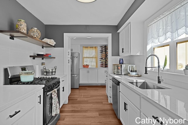 2233 Mills Ave, Muskegon, MI 49445 - kitchen featuring white cabinets, a sink, stainless steel appliances, a toaster, and backsplash
