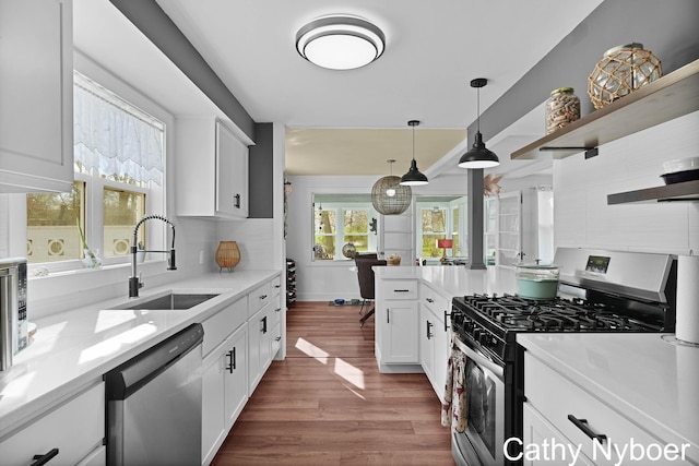 2233 Mills Ave, Muskegon, MI 49445 - kitchen featuring dark wood-style flooring, appliances with stainless steel finishes, open shelves, a sink, and light countertops