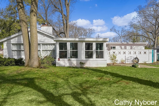 2233 Mills Ave, Muskegon, MI 49445 - back of house featuring a lawn, a chimney, and a sunroom
