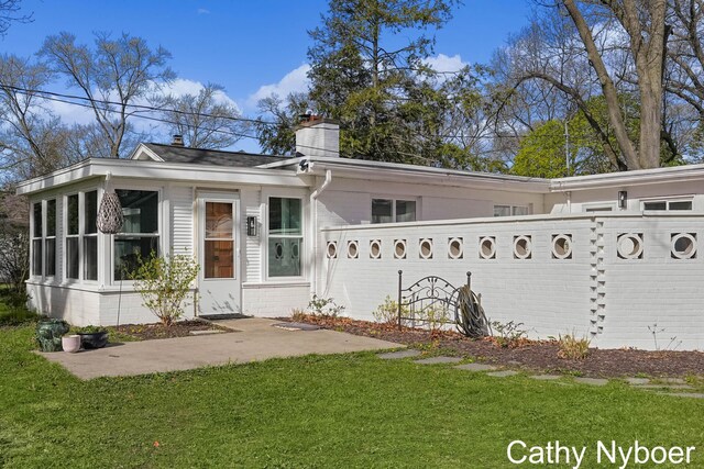 2233 Mills Ave, Muskegon, MI 49445 - view of front of home with a chimney, a front lawn, and brick siding