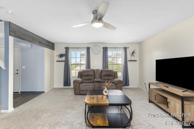 living room with ceiling fan, baseboards, and light colored carpet