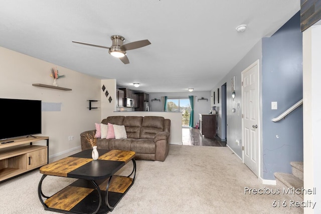 carpeted living room with stairway, a ceiling fan, and baseboards