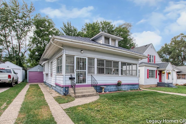 bungalow-style house with entry steps, driveway, a front yard, and roof with shingles