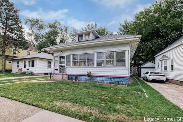 bungalow-style house with a detached garage, an outdoor structure, and a front lawn