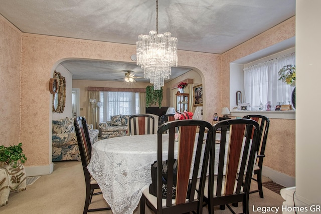dining room featuring carpet flooring, arched walkways, baseboards, and ceiling fan with notable chandelier