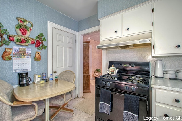 kitchen featuring black gas stove, wallpapered walls, light countertops, white cabinetry, and under cabinet range hood