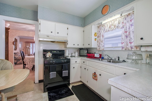 kitchen featuring a sink, black range with gas stovetop, light countertops, wallpapered walls, and under cabinet range hood