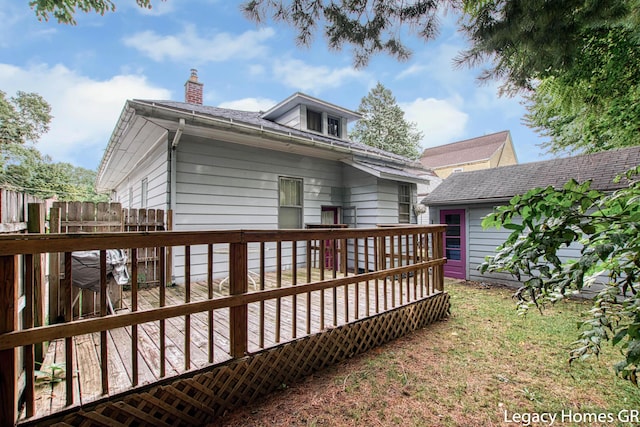 back of house featuring a wooden deck, a chimney, and fence