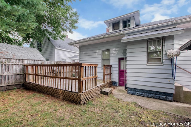 rear view of property featuring a fenced backyard, a wooden deck, and a yard