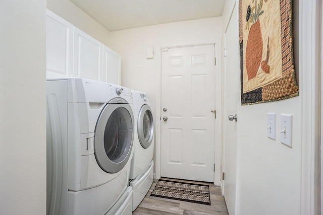 53746 Stevens Ln, Three Rivers, MI 49093 - clothes washing area with washing machine and clothes dryer, light wood-style flooring, and cabinet space