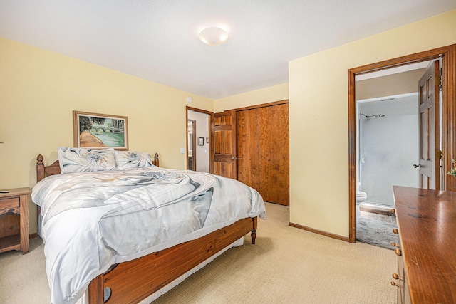 bedroom with a closet, ensuite bathroom, light carpet, and baseboards