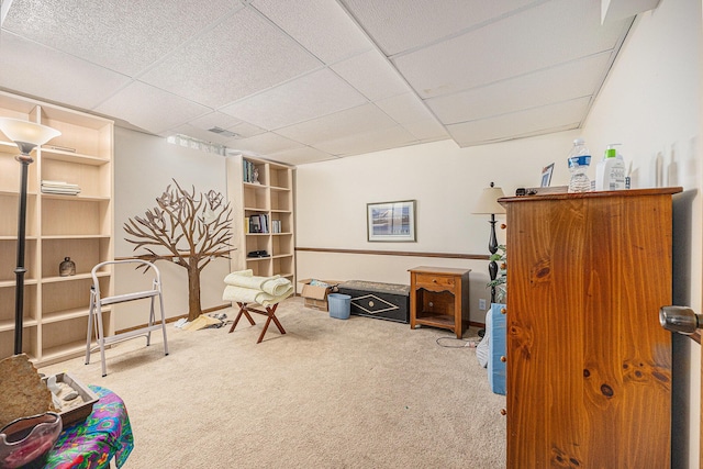 sitting room with a drop ceiling, visible vents, and carpet floors