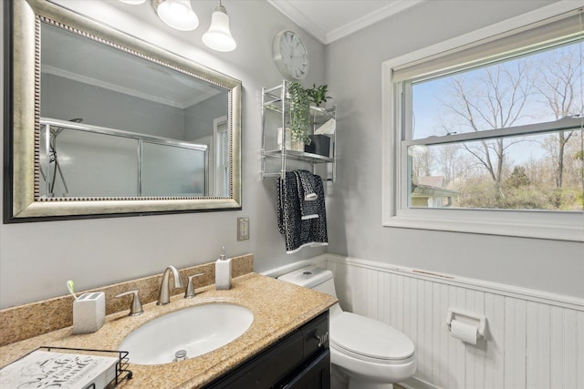 bathroom featuring a shower stall, ornamental molding, a wainscoted wall, toilet, and vanity