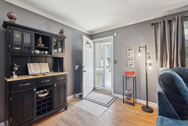 foyer entrance featuring baseboards, ornamental molding, and light wood finished floors