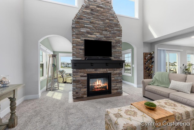 11325 Wake Dr, Allendale, MI 49401 - living area featuring carpet floors, a towering ceiling, a fireplace, arched walkways, and a wealth of natural light