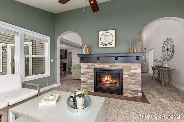11325 Wake Dr, Allendale, MI 49401 - living room featuring a glass covered fireplace, carpet floors, a ceiling fan, and arched walkways