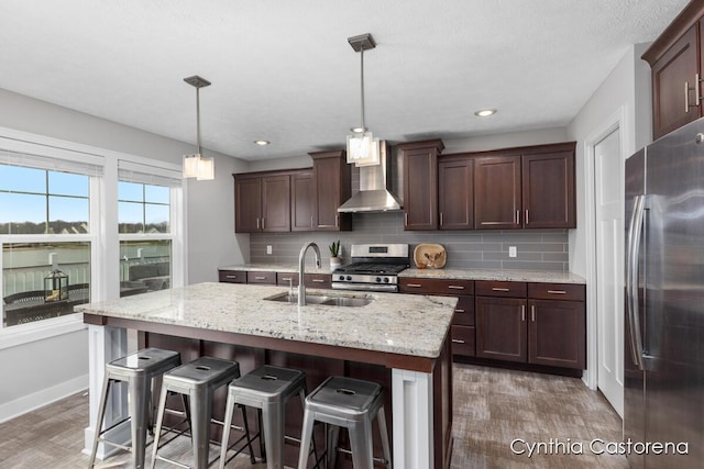 11325 Wake Dr, Allendale, MI 49401 - kitchen with appliances with stainless steel finishes, a sink, light wood finished floors, wall chimney exhaust hood, and decorative backsplash