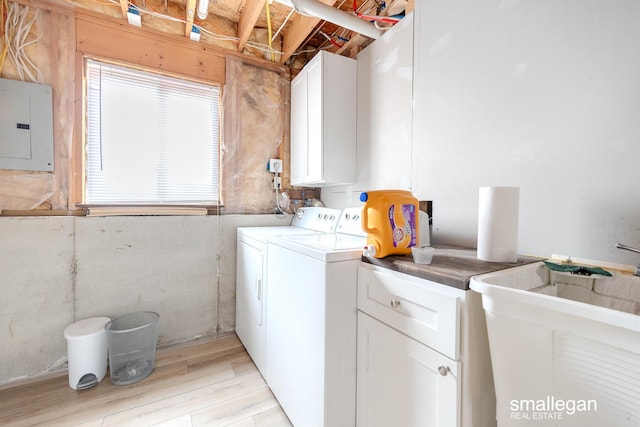 washroom featuring light wood-style floors, electric panel, separate washer and dryer, a sink, and cabinet space